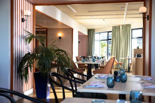 a restaurant with tables and chairs and a potted plant at The Relais Cooden Beach and Spa in Bexhill
