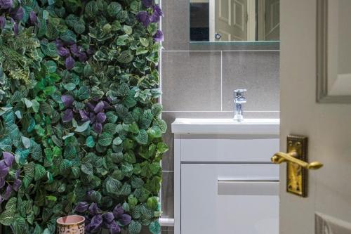 uma casa de banho com uma parede verde ao lado de um lavatório em Larger Groups Apartment with Garden and Parking em Londres