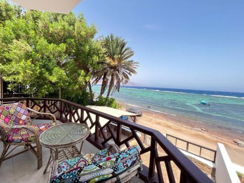 a balcony with chairs and a table and the beach at Moonlight in Dahab