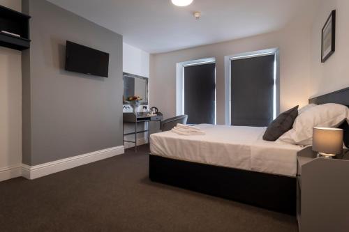 a bedroom with a bed and a desk and two windows at The Friendship Hotel in Stocksbridge
