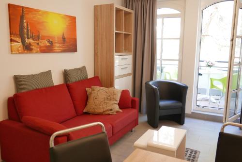 a living room with a red couch and a chair at Haus Meeresblick - Ferienwohnung Sunrise A 2.18 (Ref. 128701) in Baabe