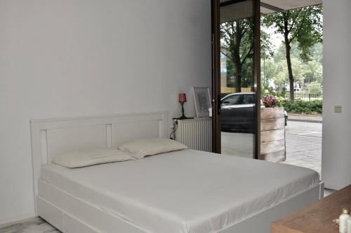 een groot wit bed in een kamer met een raam bij 010 Studio City Center Rotterdam in Rotterdam