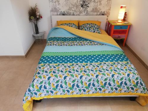 a bed with a blue and yellow comforter on it at Chambre hôtes jacuzzi climatiseur provence in Tulette