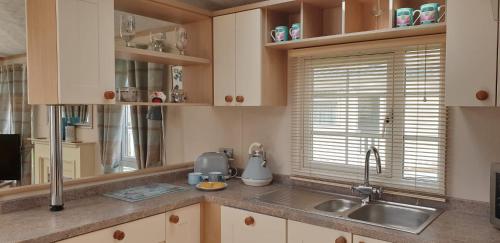 a kitchen with wooden cabinets and a sink and a window at Willow Lodge in South Cerney