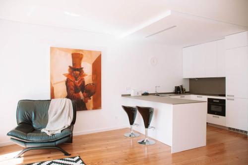 sala de estar con silla y cocina en Just Like Home - Casinhas da Vila T2 em Caminha, en Caminha