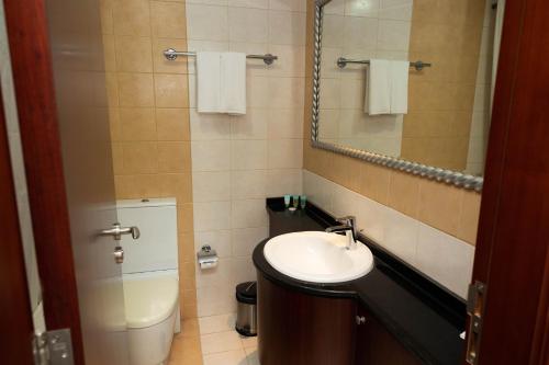 a bathroom with a sink and a toilet and a mirror at MRA Grand Hotel in Dubai