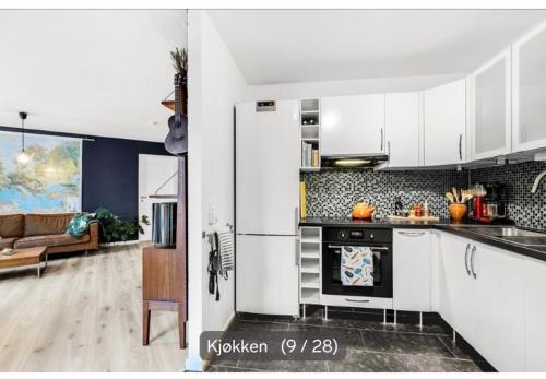 a kitchen with white cabinets and a living room at privateroomintheapartment in Oslo