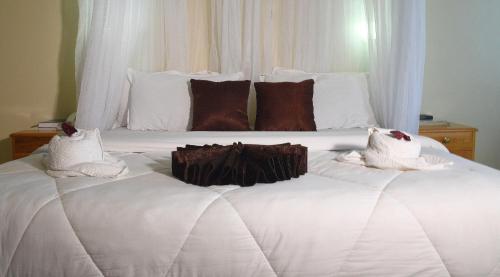 a large white bed with white sheets and brown pillows at Golf Hotel Kakamega in Kakamega
