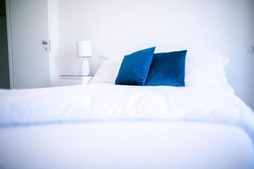 un letto bianco con due cuscini blu sopra di B&B Best Hostel Milano a Milano