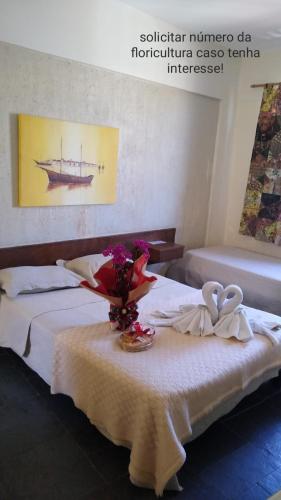 a bedroom with two beds and a table with flowers at Pousada de Ubu in Anchieta