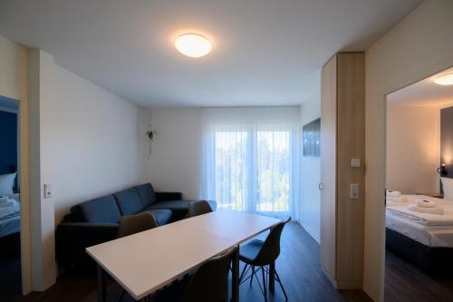 Cette chambre comprend un canapé, une table et un lit. dans l'établissement Smart & Stay Aparthotel Saarbrücken Süd - Self-Check-In - Free Parking, à Sarrebruck