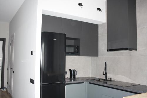 a kitchen with black cabinets and a black refrigerator at Квартира -студия с видом на море in Aktau