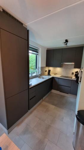 een grote keuken met zwarte kasten en een raam bij Vakantiewoning Maas en Waal in Ewijk