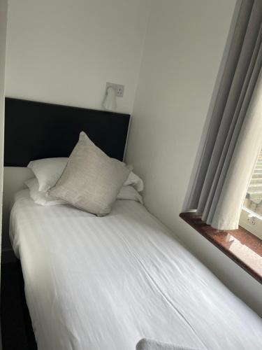 a white bed with a black headboard and a window at Kings Hotel in Newmarket