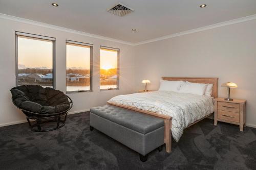 a bedroom with a bed and a chair and windows at The Lookout in Dunsborough