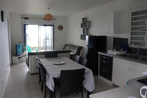 cocina y sala de estar con mesa y sillas en Le Sandivel, en Saint-Denis
