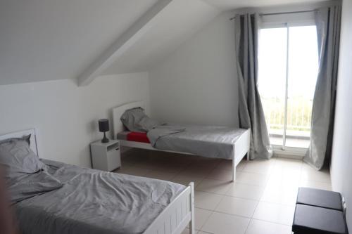 1 dormitorio con 2 camas y ventana en Le Sandivel, en Saint-Denis