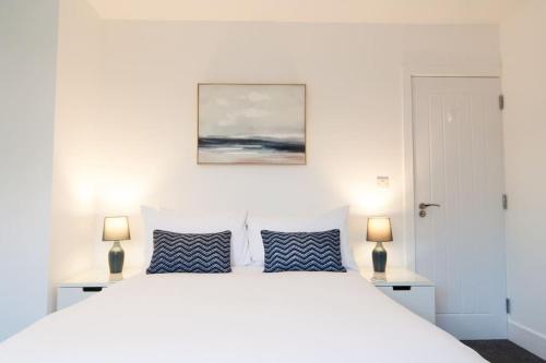 een witte slaapkamer met een wit bed en 2 lampen bij The Spitfire - Renovated 3-bed house in Cheltenham, SLEEPS 8 in Cheltenham