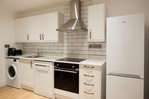 een keuken met witte kasten en een zwarte oven bij The Spitfire - Renovated 3-bed house in Cheltenham, SLEEPS 8 in Cheltenham