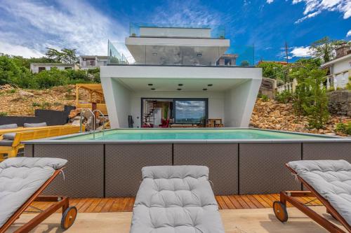 a house with a swimming pool and two chairs at Villa SPA DECK 1, DECK 2, DECK 3 in Dramalj