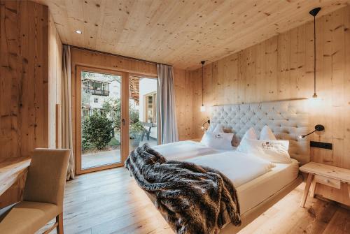 ein Schlafzimmer mit einem großen Bett und einem Fenster in der Unterkunft Presulis Apartments & Restaurant in Völs am Schlern