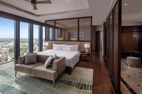 a bedroom with a bed and a couch and windows at Melia Vinpearl Hue in Hue