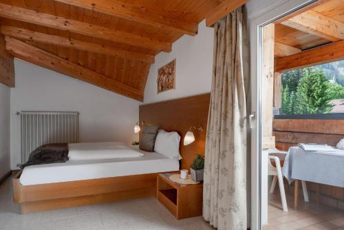 a bedroom with a bed and a large window at A. Paolo Apartments in Vigo di Fassa