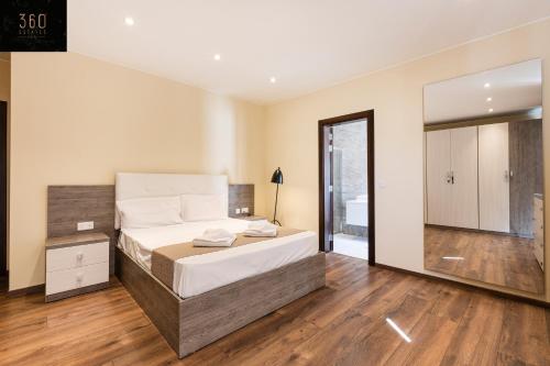 Un dormitorio con una cama y un espejo grande. en Seafront, Designer APT with Private Terrace & WIFI by 360 Estates, en Tal-Pietà