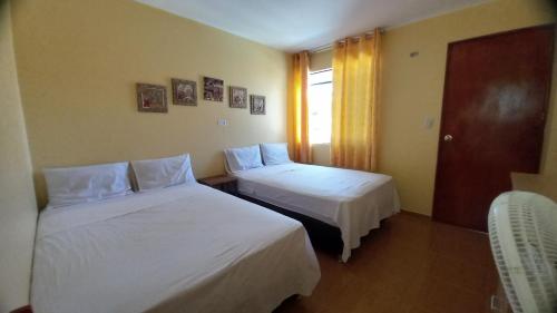 a hotel room with two beds and a window at Hospedaje Ola Marina in Máncora