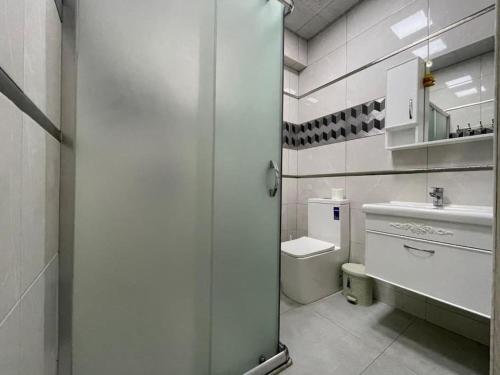 a white bathroom with a toilet and a sink at Park Azure Modern apartment in Baku