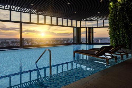a swimming pool on top of a building with a sunset at Melia Vinpearl Hue in Hue