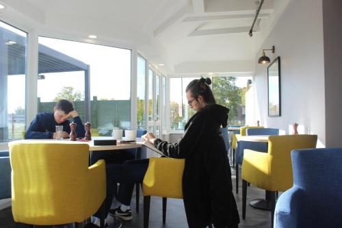 a woman standing in front of a table in a restaurant at Holiday Inn Kenilworth - Warwick by IHG in Kenilworth
