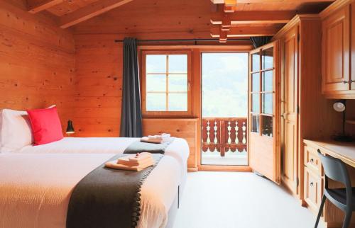 a bedroom with two beds and a large window at Chalet La Pala in Val-d'Illiez