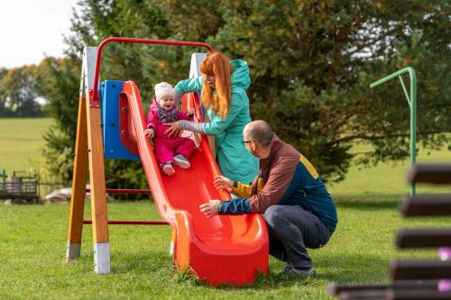a man and a woman playing with a child on a slide at Jasenka rekreační středisko Zubří in Nové Město na Moravě