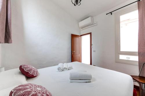una camera bianca con un grande letto bianco con cuscini rossi di In Piazza 'Apartments & Relax' a Ravenna