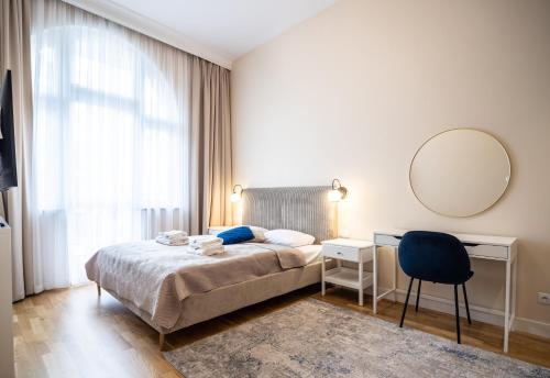 a bedroom with a bed and a desk and a mirror at Apartos Wisus - Luxury Apartments in Świnoujście