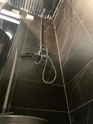 a shower in a bathroom with a black tiled wall at DARTAD APARTMENT in Ohrid