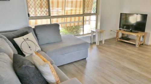 a living room with a couch and a television at 25 Admiralty Court, Yamba in Yamba