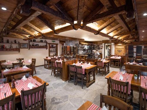 a restaurant with tables and chairs in a room at Hotel Olympic - Montana Center in Crans-Montana