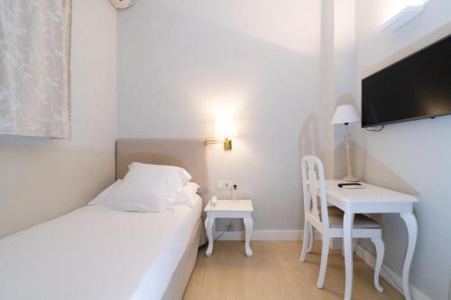 Habitación blanca pequeña con cama y escritorio en Hotel Niza, en San Sebastián