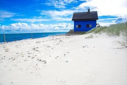 un edificio azul sentado en la playa cerca del océano en exclusives Hausboot "Tante Trost" en Heiligenhafen