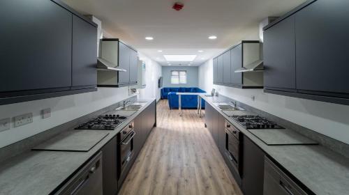 uma grande cozinha com armários pretos e pisos de madeira em Lovely Studio in Selly Oak 10 mins from city! em Birmingham