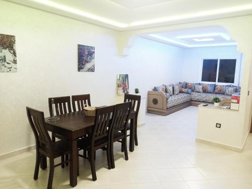 a dining room with a table and chairs and a couch at NOUVEAU Appartement Totalement neuf - très propre à coté du centre commercial MARJANE in Tangier