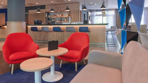 eine Lobby mit roten Stühlen und Tischen sowie eine Bar in der Unterkunft Holiday Inn Express Berlin City Centre, an IHG Hotel in Berlin