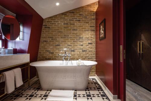 a bath tub in a bathroom with a brick wall at Sun Street Hotel Shoreditch in London
