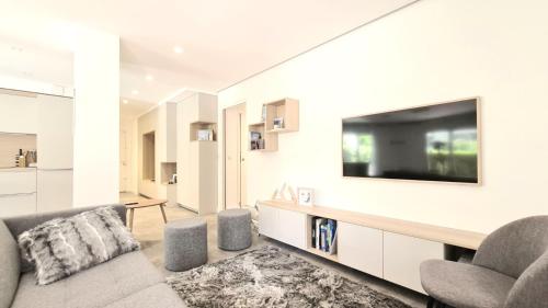 un salon avec un canapé et une télévision dans l'établissement Proche du lac et des commerces, appartement neuf, au calme, avec 3 chambres et une grande terrasse, à Annecy