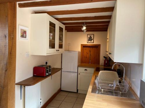 a kitchen with white cabinets and a red appliance at Thames Cottage, Old Mill Farm, Cotswold Water Park in Cirencester