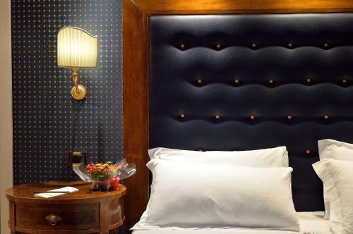 a bedroom with a bed with a blue headboard and a table at Hotel Homs in Rome