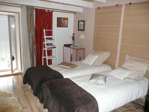 two twin beds in a room with a window at La Belle des Champs in Saint-Andelain