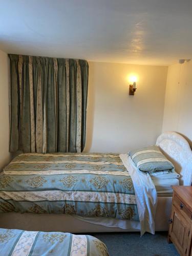 a bedroom with two beds and a window with curtains at Thames Cottage, Old Mill Farm, Cotswold Water Park in Cirencester